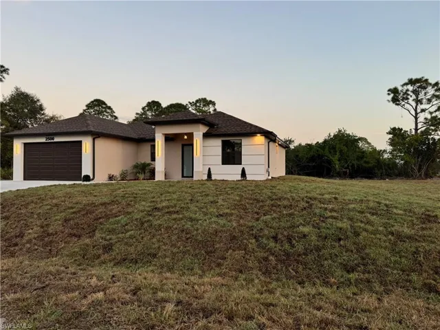 View of front of property featuring a garage and a yard