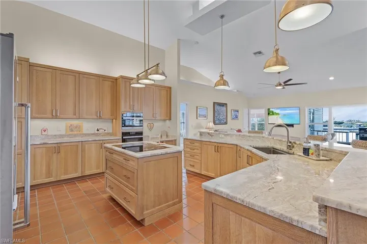 Kitchen featuring sink, hanging light fixtures, ceiling fan, light tile patterned floors, and a kitchen island