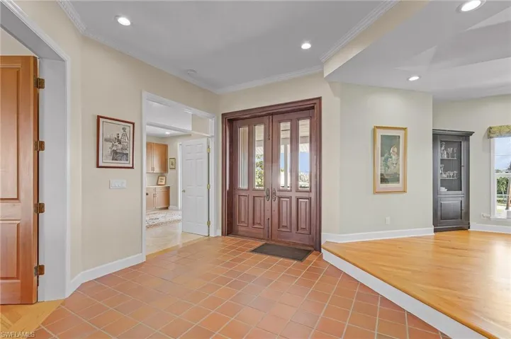 Foyer with ornamental molding, tile patterned floors, and a healthy amount of sunlight