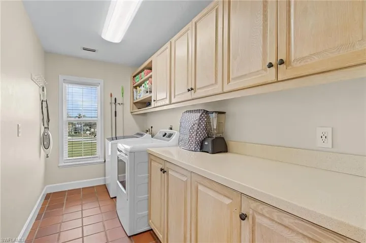 Laundry area featuring cabinets, light tile patterned floors, and washing machine and dryer