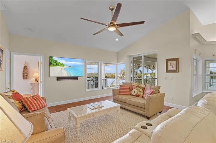 Living room with light tile patterned floors, ceiling fan, and lofted ceiling