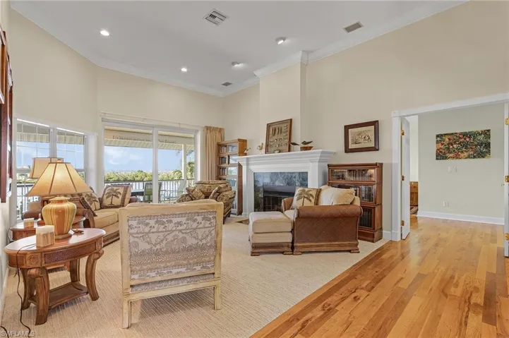 Living room with light wood-type flooring, ornamental molding, a tile fireplace, and a high ceiling
