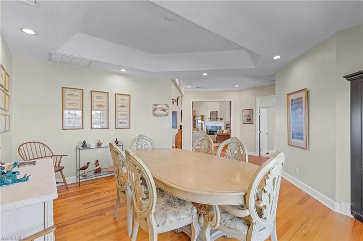 Dining area with light hardwood / wood-style floors and a raised ceiling