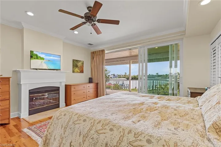 Primary bedroom with ceiling fan, fireplace, crown molding, and access to outside