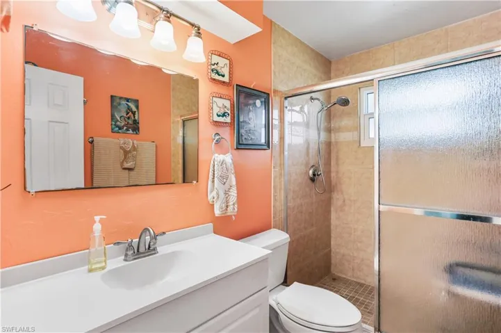 Bathroom featuring a shower with door, toilet, and vanity