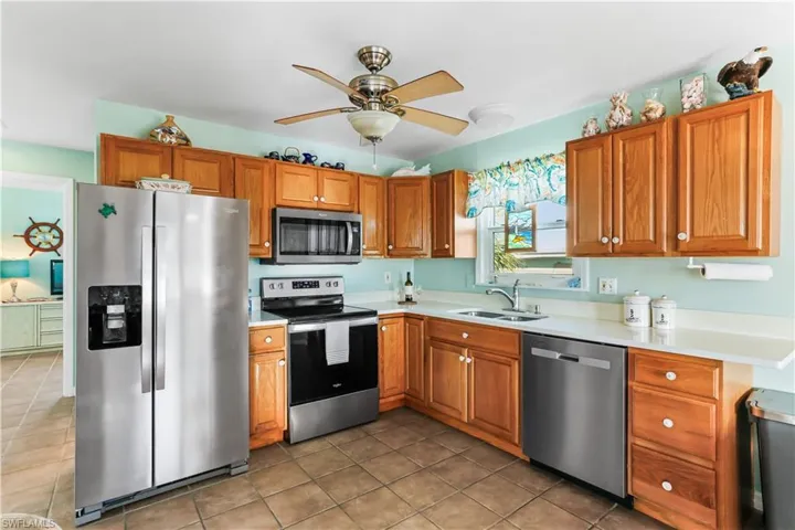 Kitchen featuring sink, appliances with stainless steel finishes, tile patterned flooring, and ceiling fan