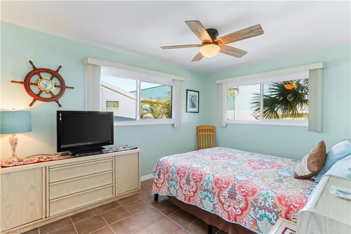 Tiled bedroom featuring ceiling fan