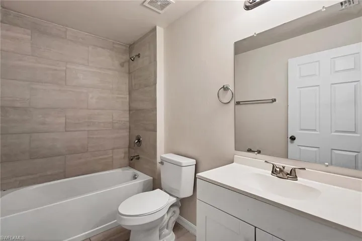 Full bathroom featuring tiled shower / bath, vanity, and toilet