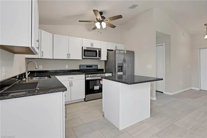 Kitchen featuring white cabinets, a kitchen island, stainless steel appliances, sink, and light tile floors