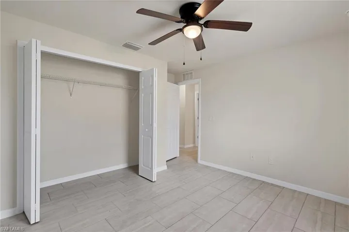 Unfurnished bedroom featuring a closet, ceiling fan, and light tile floors