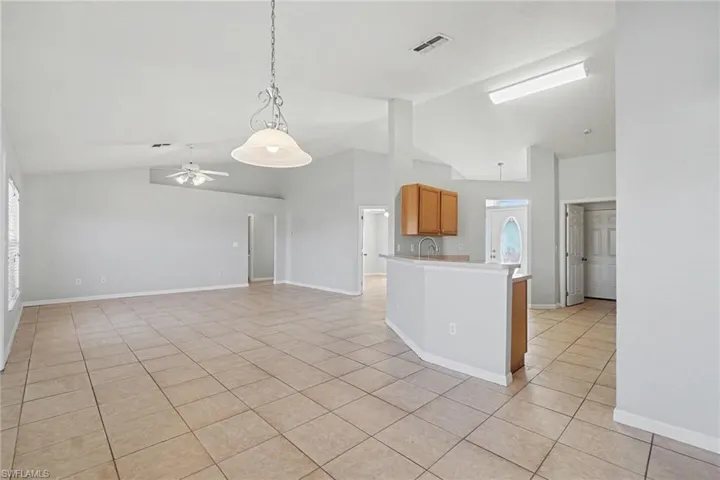 Kitchen featuring pendant lighting, ceiling fan, vaulted ceiling, open floor plan, and light tile patterned floors