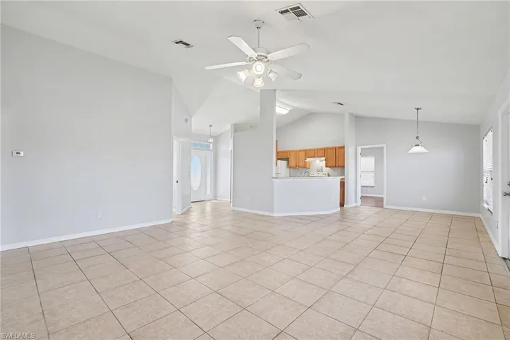 Unfurnished living room with ceiling fan, light tile patterned flooring, and vaulted ceiling
