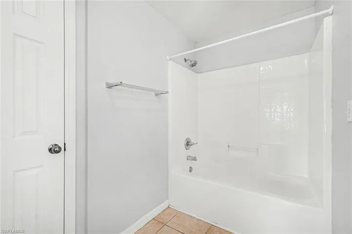 Bathroom with shower / tub combination and light tile patterned flooring