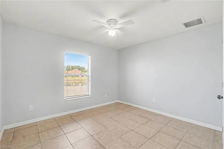 Empty room with a ceiling fan and light tile patterned floors