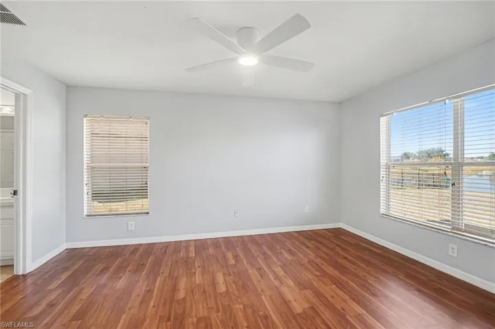 Empty room featuring dark wood-type flooring and ceiling fan