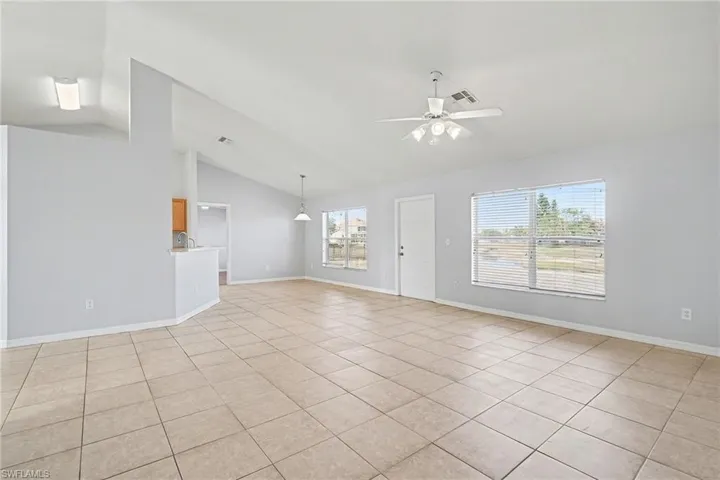 Unfurnished room featuring lofted ceiling, a ceiling fan, and light tile patterned flooring