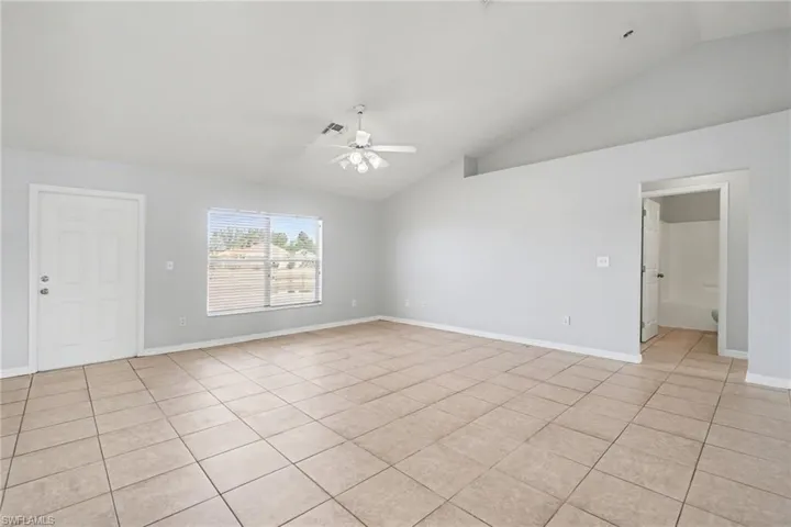 Spare room with a ceiling fan, lofted ceiling, and light tile patterned floors