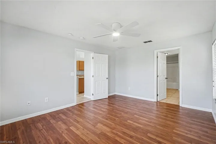 Unfurnished bedroom with ceiling fan, light wood-type flooring, and ensuite bathroom