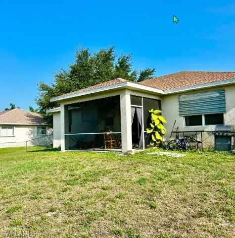 Rear view of house with a sunroom and a lawn