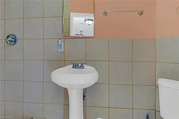 Bathroom with toilet and tile walls