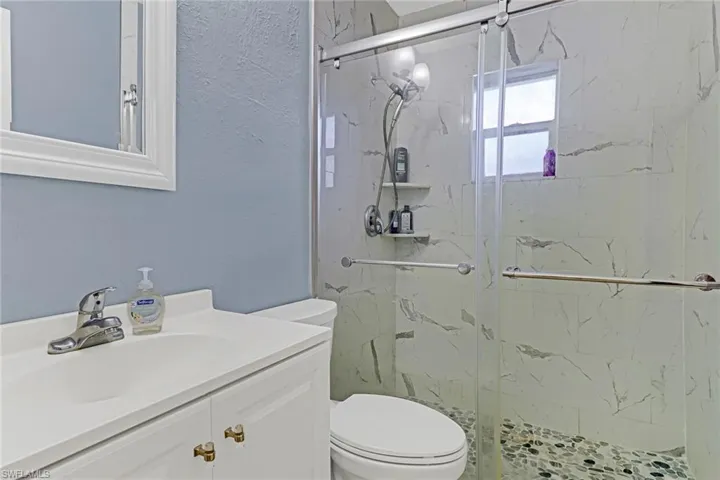 Bathroom with an enclosed shower, toilet, and vanity