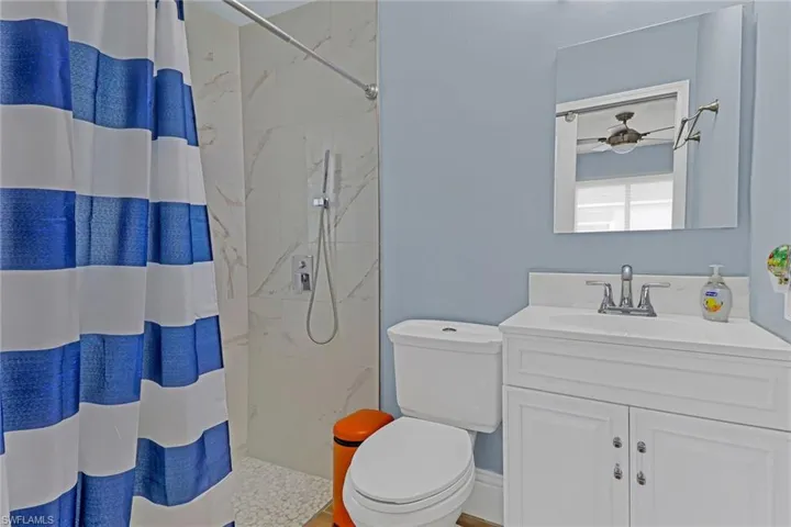 Bathroom with a shower with curtain, vanity, and toilet