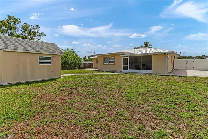 Rear view of property featuring a sunroom and a yard