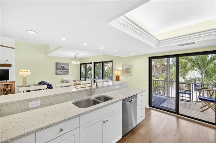 Kitchen with dishwasher, white cabinetry, plenty of natural light, wood finished floors, and crown molding