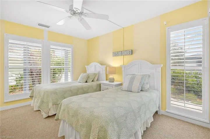 Carpeted bedroom with multiple windows and a ceiling fan