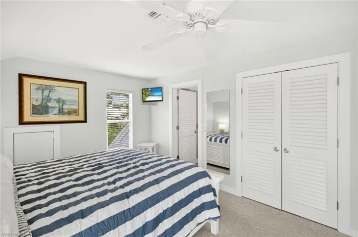 Carpeted bedroom with a ceiling fan and a closet