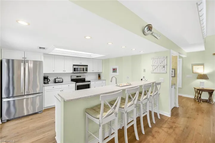 Kitchen featuring appliances with stainless steel finishes, a breakfast bar, white cabinetry, and recessed lighting