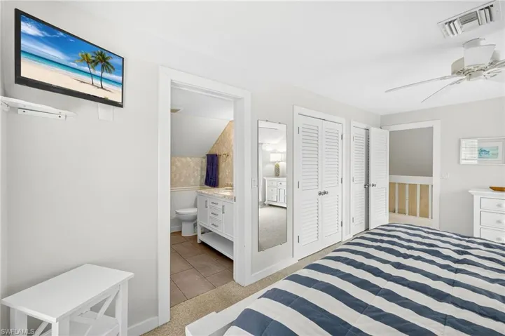 Bedroom featuring light tile patterned flooring, a ceiling fan, and connected bathroom
