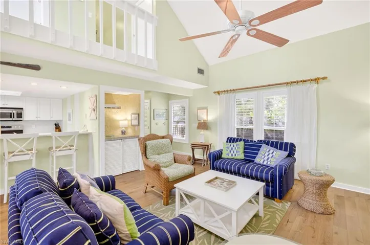 Living area with light wood finished floors, high vaulted ceiling, and a ceiling fan