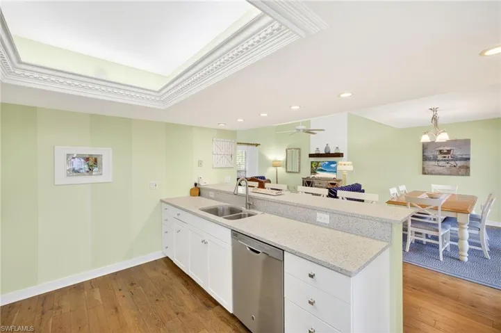 Kitchen with dishwasher, a peninsula, dark wood-style flooring, white cabinetry, and recessed lighting