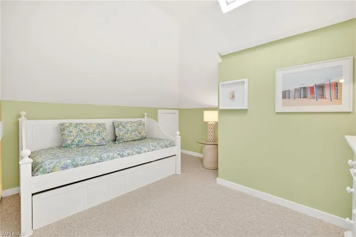 Carpeted bedroom with lofted ceiling and baseboards