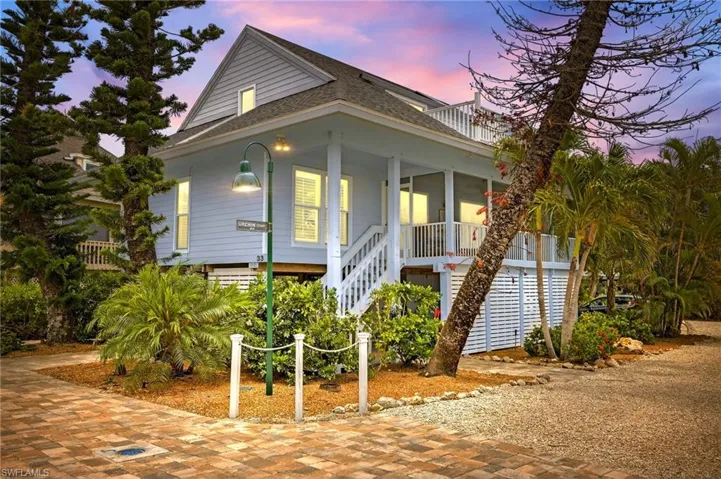 Beach home featuring stairway, a shingled roof, and covered porch