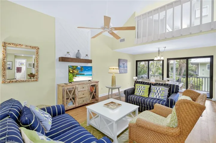 Living room with wood finished floors, a ceiling fan, and a towering ceiling
