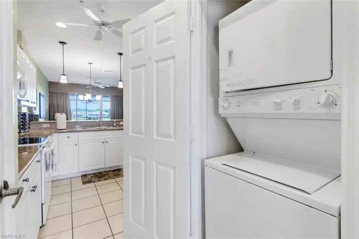 Laundry room with ceiling fan, light tile patterned floors, sink, and stacked washer and clothes dryer