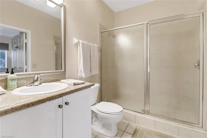 Bathroom with toilet, vanity, tile patterned floors, and a shower with shower door