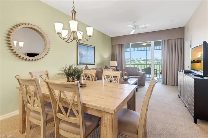 Carpeted dining room featuring ceiling fan with notable chandelier