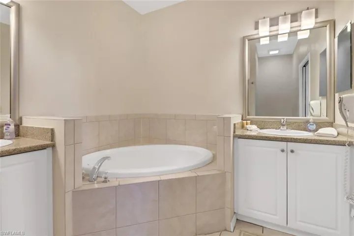 Bathroom with tile patterned floors, vanity, and tiled bath