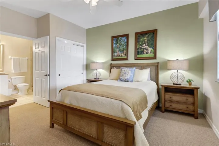 Carpeted bedroom featuring a closet, ensuite bathroom, and ceiling fan