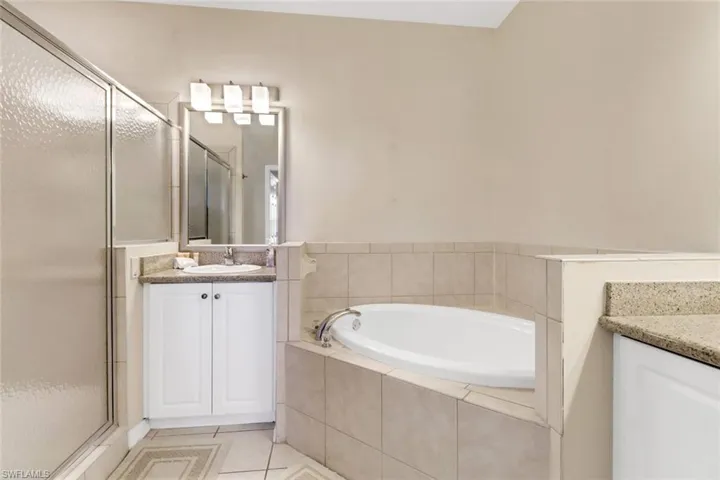 Bathroom with tile patterned floors, vanity, and shower with separate bathtub