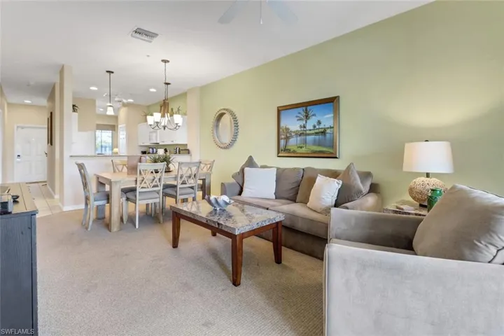 Carpeted living room featuring ceiling fan with notable chandelier
