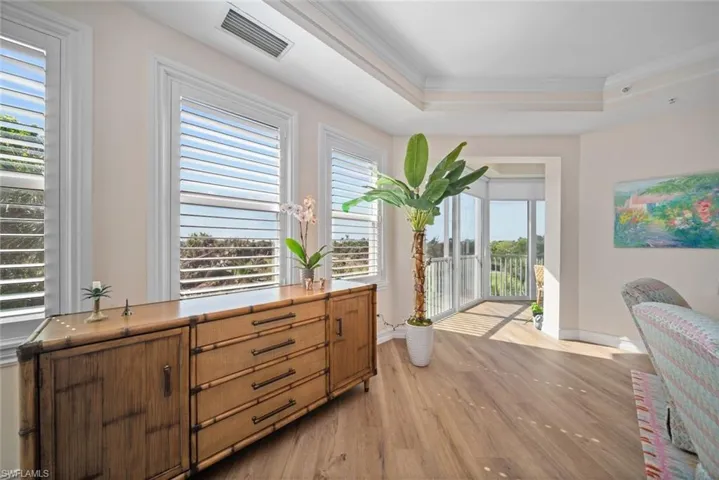 Sitting room with plenty of natural light, ornamental molding, a tray ceiling, and light hardwood / wood-style flooring