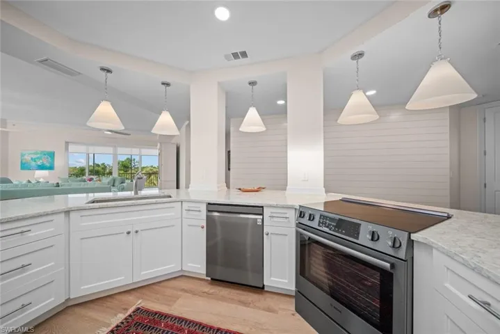 Kitchen featuring appliances with stainless steel finishes, white cabinetry, hanging light fixtures, and sink