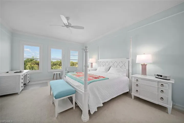 Bedroom featuring ceiling fan, ornamental molding, and light carpet