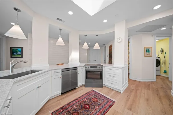 Kitchen with kitchen peninsula, sink, light hardwood / wood-style flooring, appliances with stainless steel finishes, and white cabinetry