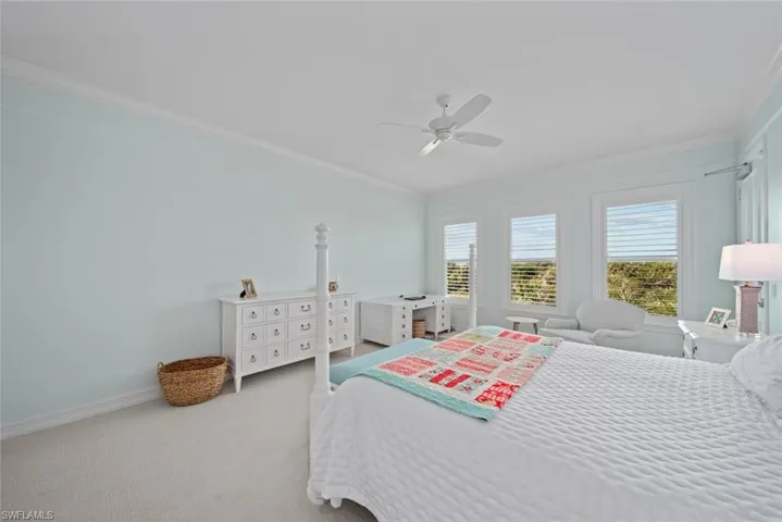 Carpeted bedroom with ceiling fan and ornamental molding