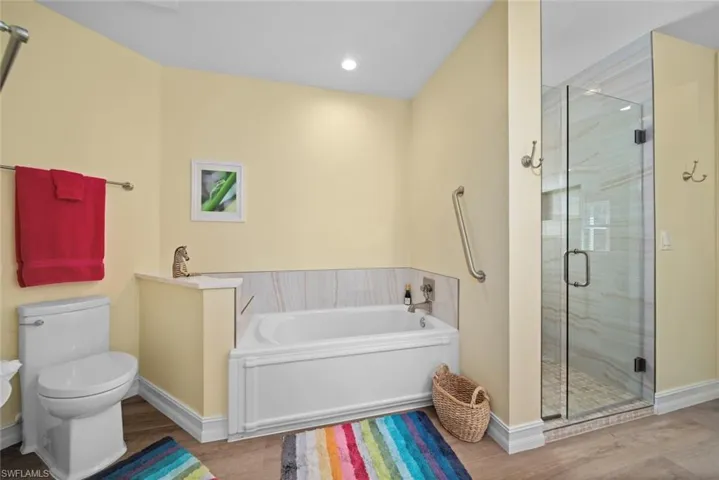 Bathroom featuring hardwood / wood-style floors, plus walk in shower, and toilet